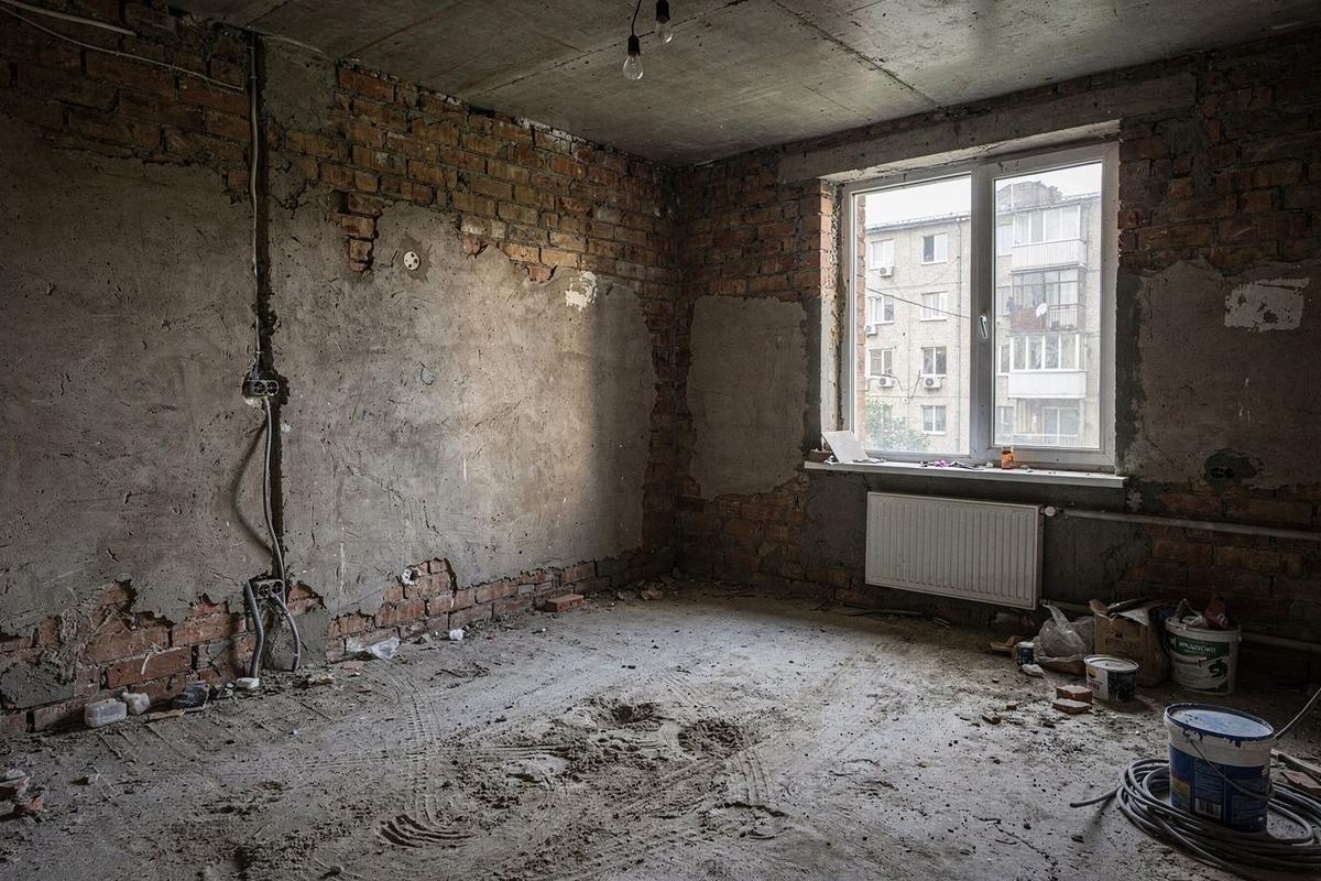The same Kyiv living room before renovation, stripped back to brick and bare concrete